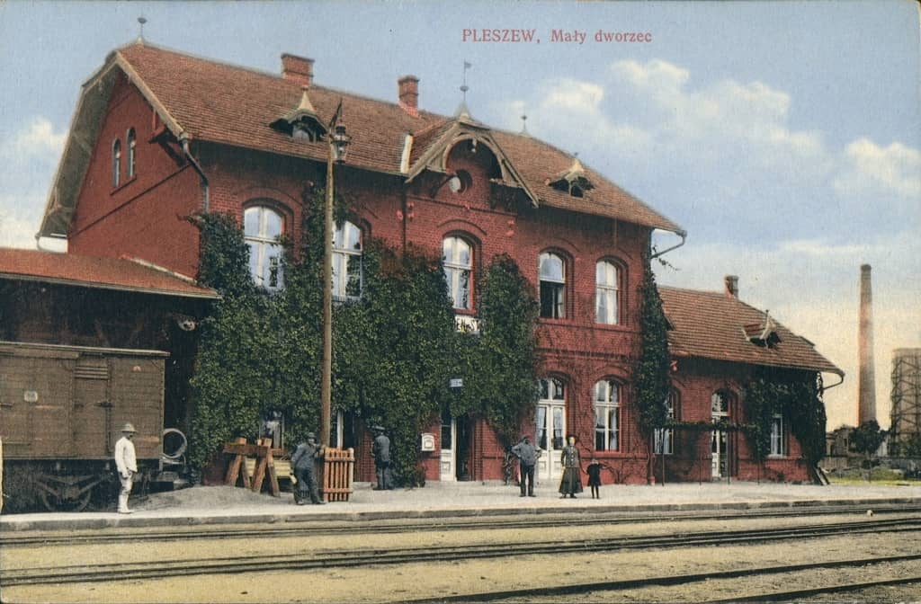 Zdjecie archiwalne przedstawia dworzec kolejowy w Pleszewie oraz podróżnych